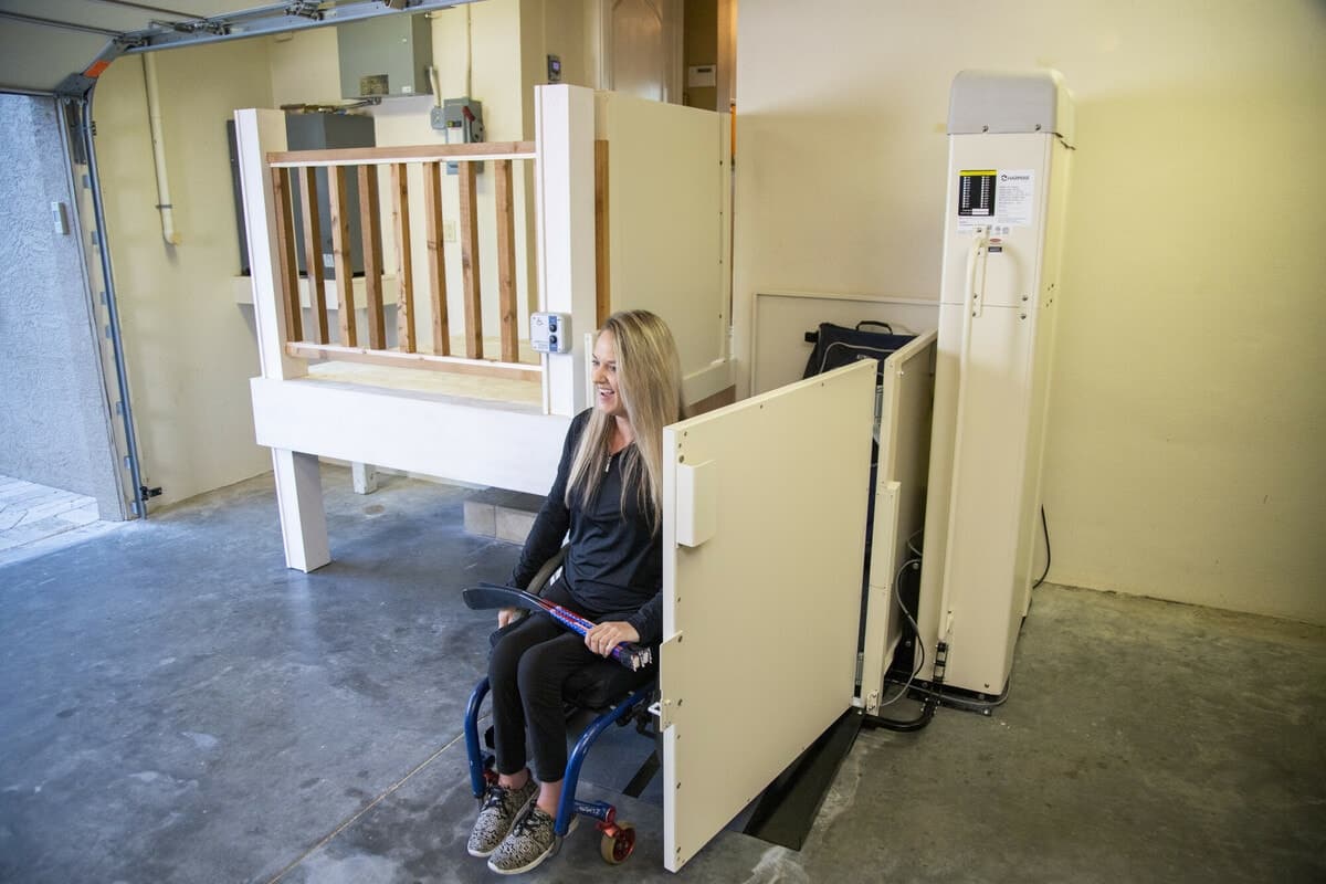 woman safely exiting platform lift installed in garage by Lifeway Mobility