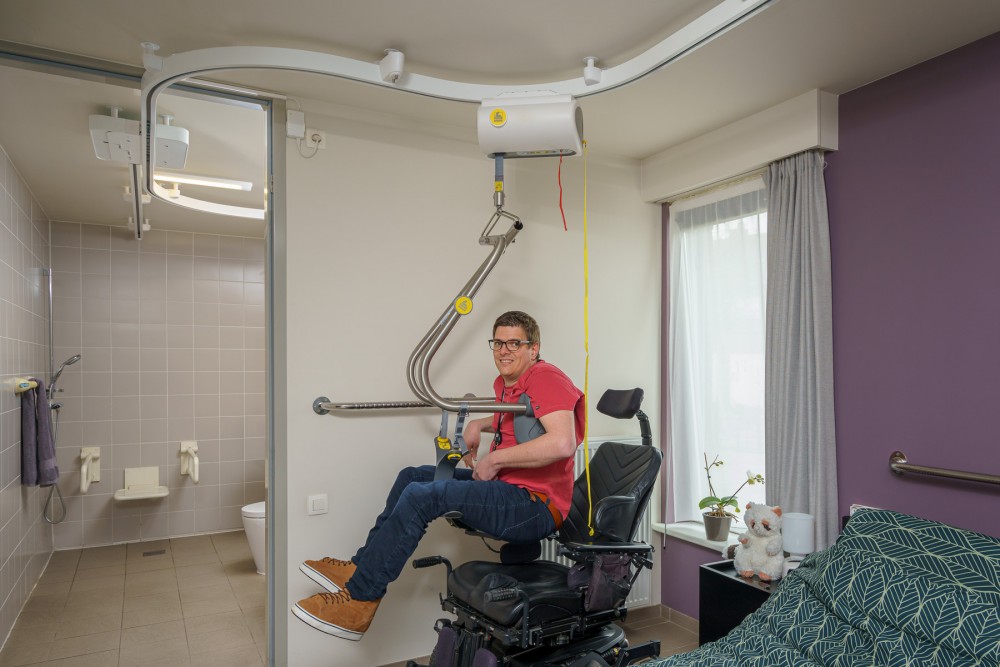 man in ceiling lift safely transferring to bathroom