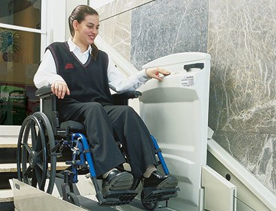 woman in wheelchair using inclined platform lift to safely access lower landing of place of worship