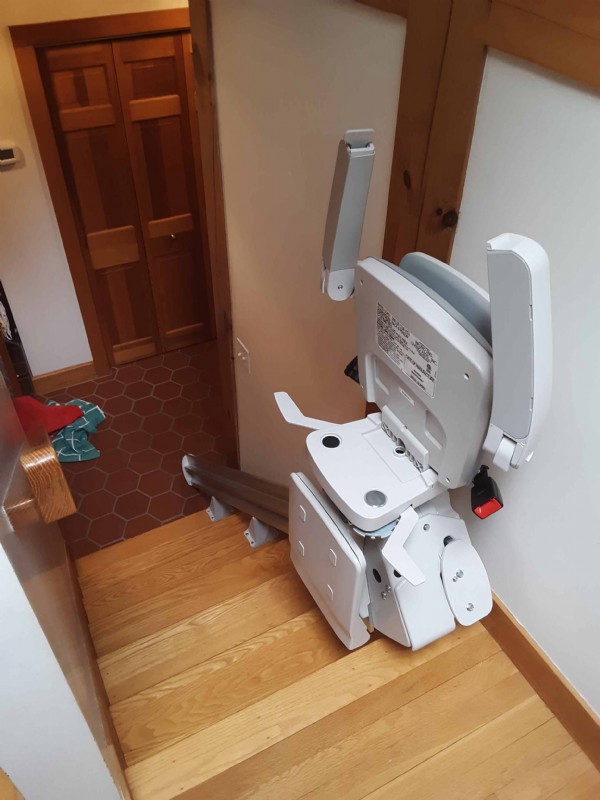 Bruno Elan stairlift components folded up at top landing in home in Weston Massachusetts
