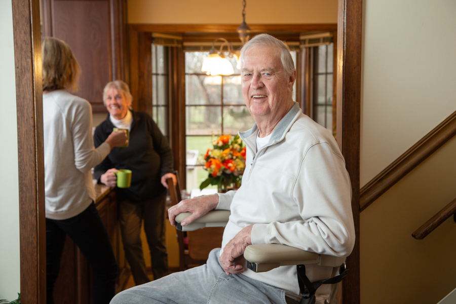 Man smiling while sitting on a stair lift